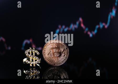 Eine Bitcoin-Münze liegt neben einem mit Diamanten besetzten Anhänger der Dollarkette Stockfoto