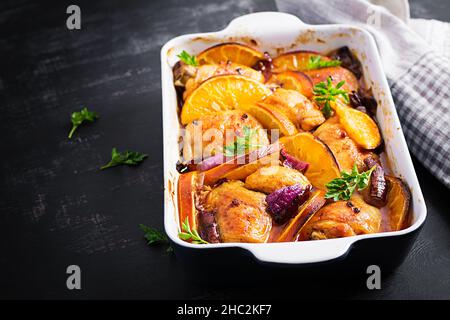 Gebackene Hähnchenschenkel. Appetitliche Scheiben gebackenes Huhn mit roten Zwiebeln und Orangen in einer Auflaufform. Stockfoto