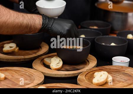 Kochvorgang der Suquet de Peix-Suppe mit Kartoffeln, Kräutern und Fisch mit der Zugabe von Picada close-up in einem Topf auf dem Tisch. Stockfoto