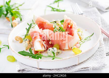 Vorspeise mit Birne, Blauschimmelkäse und Schinken für den Urlaub auf einem weißen Teller. Stockfoto