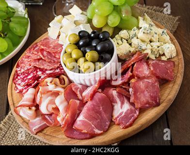 Antipasti Teller mit Speck, Trockenfleisch, Salami, Käse und Trauben auf einem hölzernen Hintergrund catering Stockfoto