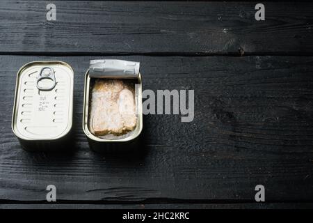 Set aus Wildrosa Lachs aus Dosen, in Blechdose, auf schwarzem Holztischhintergrund, mit Textraum und Platz für Text Stockfoto
