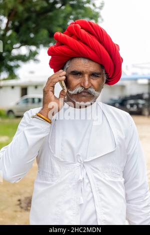 JAWAI, Rajasthan, Indien - September 2021: Porträt eines älteren Mannes der ethnischen Gruppe der Rabari in einem nationalen Kopfschmuck und einem traditionellen weißen Kleid. Stockfoto