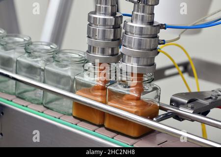 Gläser mit Rahmhonig in einer Verpackungslinie in einer kommerziellen Honigfabrik Stockfoto