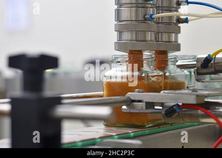 Gläser mit Rahmhonig in einer Verpackungslinie in einer kommerziellen Honigfabrik Stockfoto