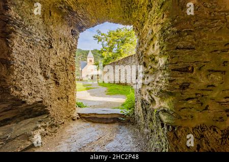 Gewölbte Tür mit einer dicken Steinmauer, die zum äußeren Innenhof der Burgruine von Esch-sur-sure führt, Tempel im Hintergrund, sonniger Sommertag i Stockfoto