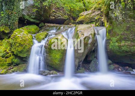 Schiessentümpel Wasserfall, Fluss Black Ernz mit kalkhaltigem kristallklarem Wasser, das zwischen moosbedeckten Felsen fließt, Vegetation im Hintergrund, Mull Stockfoto