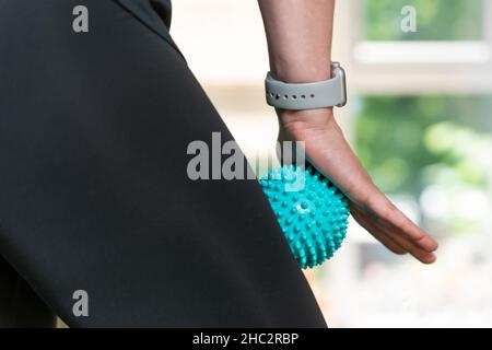 Frau, die ein Massagewerkzeug für die Myofaszialtherapie an den Oberschenkelmuskeln verwendet. Rolle für die Physiotherapie Stockfoto