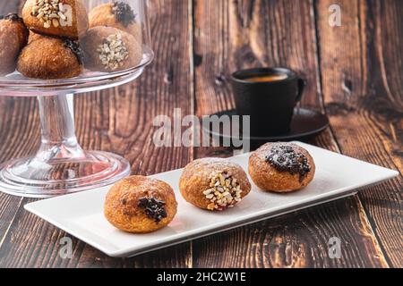 Bombolon oder Bomboloni ist ein italienisches gefülltes Donut- und Snackfutter. Deutsche Krapfen - Krapfen oder berliner - gefüllt mit Marmelade und Schokolade Stockfoto