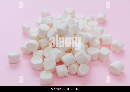 Marshallows Haufen auf pastellrosa Hintergrund. Weiße flauschige Mini-Dessert, süße Kinder Geburtstagsfeier Snack, Nahaufnahme Stockfoto