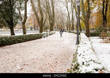 Pamplona, Spanien - 28. November 2021 - Menschen, die durch die verschneiten Gärten des Parque de la Taconera schlendern. Stockfoto