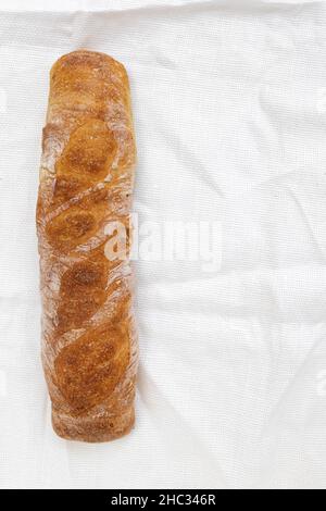 Ganzer Laib frisches Brot isoliert auf Sackleinen, Draufsicht, französisches Baguette mit leerem Platz für Text Stockfoto