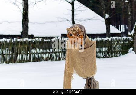 Puppe der Kreatur mit Bart in Meteņi Mumming Maske und Kostüm Aufenthalt im verschneiten Hof Stockfoto