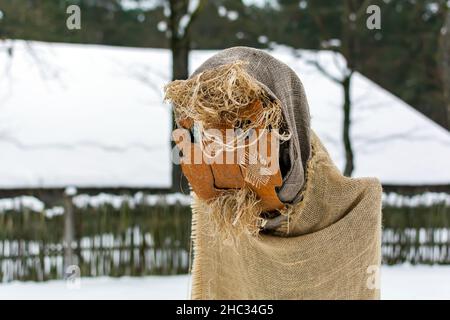 Puppe der Kreatur mit Bart in Meteņi Mumming Maske und Kostüm Aufenthalt im verschneiten Hof Stockfoto