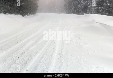 Winterwaldstraße bedeckt mit Eis und Schnee. Gefährliche Fahrbedingungen Stockfoto