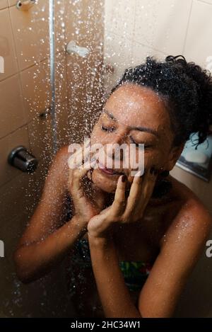 Porträt einer Frau im Badezimmer, die sich wäscht. Salvador, Bahia, Brasilien. Stockfoto