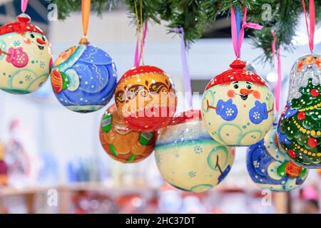 Weihnachtskugeln aus Holz – Schneemänner auf bunten Bändern. Stockfoto