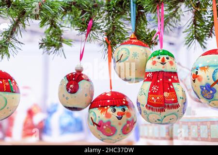 Weihnachtskugeln aus Holz – Schneemänner auf bunten Bändern. Stockfoto