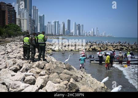 Polizisten beobachten Fischer, die am Strand von Bocagrande in Cartagena de Indias, Kolumbien, arbeiten Stockfoto