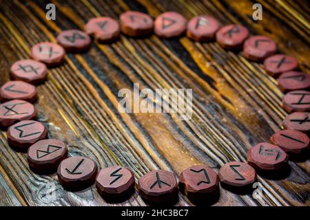 Rune kreist auf einem Holztisch, Ältester Futhark. Rote Runen aus Holz geschnitzt Stockfoto