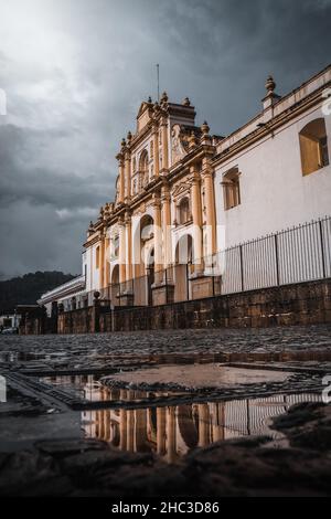 Catedral de Santiago Reflexion über den Plaza Mayor, gefangen in einer Pfütze. Ort Antigua Guatemala, Guatemala. Stockfoto