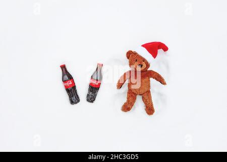 Teddybär bei der Herstellung von Schneeengel, zwei Flaschen Cola für Weihnachtsfeier, Blick von oben, Moskau, 12. Dezember 2021 Stockfoto