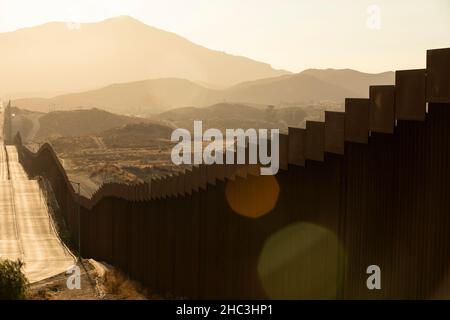 Am Nachmittag scheint der Sonnenuntergang an der Grenzmauer zwischen den USA und Mexiko in der Innenstadt von Tecate, Baja, Mexiko. Stockfoto