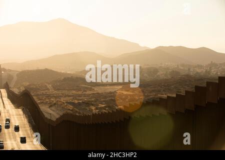 Am Nachmittag scheint der Sonnenuntergang an der Grenzmauer zwischen den USA und Mexiko in der Innenstadt von Tecate, Baja, Mexiko. Stockfoto