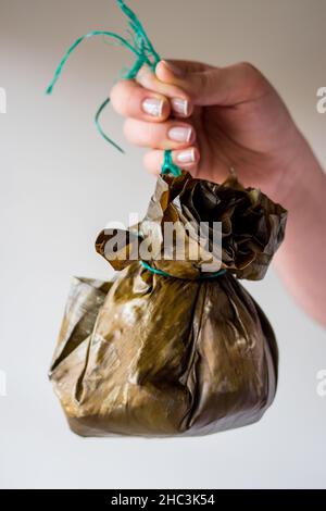 Nehmen Sie ein traditionelles kolumbianisches Essen, das als „Tamal“ bekannt ist und mit Blättern eingewickelt ist Stockfoto