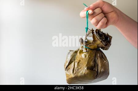 Nehmen Sie ein traditionelles kolumbianisches Essen, das als „Tamal“ bekannt ist und mit Blättern eingewickelt ist Stockfoto