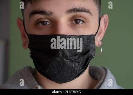 Junger Mann mit einer Maske und Blick auf die Kamera Stockfoto