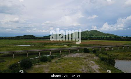 Luftaufnahme dieser erhöhten Eisenbahn, Berge und Bauernhöfe in Thailand Stockfoto