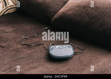 Tragbarer cd-Player, bekannt als Diskman, der sich zu Hause auf dem Sofa lehnt Stockfoto