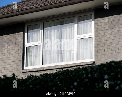 Weißer Fensterrahmen auf grauer Ziegelwand Stockfoto