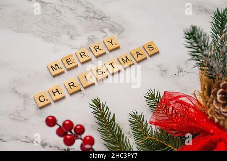 Beschriftende Holzfliesen bilden die Worte Frohe Weihnachten mit weihnachtsdekoration Stockfoto