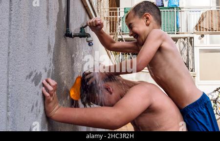 Kinder, die an einem schönen Sommertag mit Wasser spielen, stehen im Fokus Stockfoto