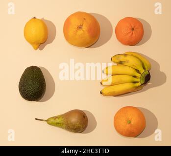 Ordentlich angerichtet frisches Obst auf sandfarbenem Hintergrund. Minimale flache Verlegung. Stockfoto