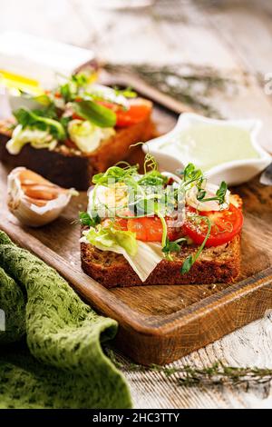 Nahaufnahme Toast mit gesalzenem Fisch, Käse, Ei, Zwiebelringen und Salat. Appetitliche Canapes oder Sandwiches mit geräuchertem Lachs. Leckeres Frühstück Stockfoto
