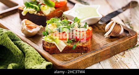 Lebensmittelbanner. Toast mit gesalzenem Fisch, Käse, Eiern, Zwiebelringen und Salat. Appetitliche Canapes oder Sandwiches mit geräuchertem Lachs. Traditionelles Frühstück Stockfoto