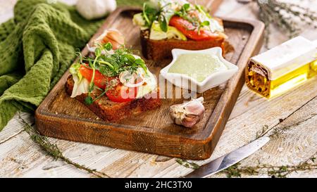 Lebensmittelbanner. Appetitliche Canapes oder Sandwiches mit gesalzenem Lachs. Toast mit geräuchertem Fisch, Weichkäse, Eiern, Zwiebelringen und frischem Salat. Stockfoto