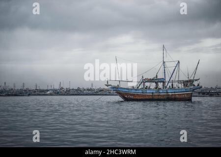 Graustufenaufnahme eines alten Schiffes, das unter dunklen Sturmwolken im Meer segelt, Karatschi-Küste, Pakistan Stockfoto