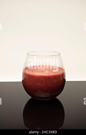 Vertikale Aufnahme eines Glases Fruchtmoothie auf dem Tisch Stockfoto