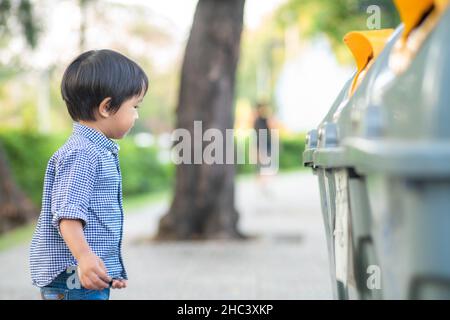 Bezaubernder kleiner Junge, der den Müll in einem ökologischen Park sauber hält Stockfoto