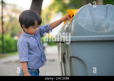 Bezaubernder kleiner Junge, der den Müll in einem ökologischen Park sauber hält Stockfoto