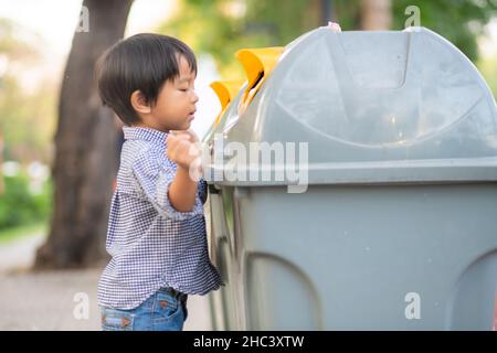 Bezaubernder kleiner Junge, der den Müll in einem ökologischen Park sauber hält Stockfoto