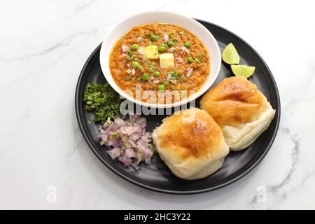 Pav Bhaji im indischen Stil der Mumbai Street, garniert mit Erbsen, rohen Zwiebeln, Koriander und Butter. Mit pav gebratene. Stockfoto