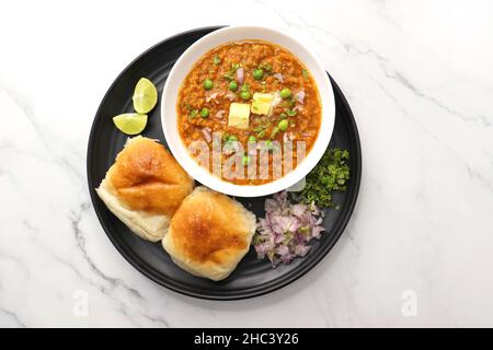 Pav Bhaji im indischen Stil der Mumbai Street, garniert mit Erbsen, rohen Zwiebeln, Koriander und Butter. Mit pav gebratene. Stockfoto