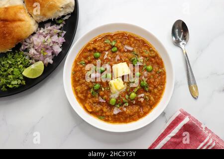 Pav Bhaji im indischen Stil der Mumbai Street, garniert mit Erbsen, rohen Zwiebeln, Koriander und Butter. Mit pav gebratene. Stockfoto