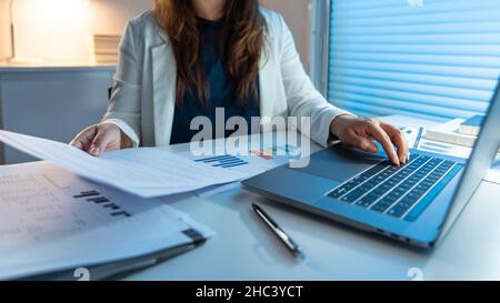 Überarbeitungs-Konzept die Frau, die ihre Arbeit spät in der Nacht macht, indem sie Papiere liest und sie auf das Notizbuch schreibt. Stockfoto