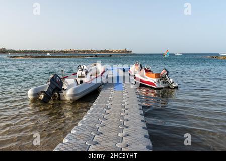 Hurghada, Ägypten - 01. Juni 2021: Gummiboot und Jetskis am Pier, der zum Meer in der Makadi Bay führt, einer von Ägyptens wunderschönen Roten Meer Riv Stockfoto